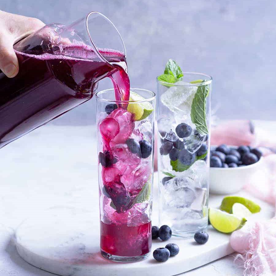 hand pours a blueberry mocktail