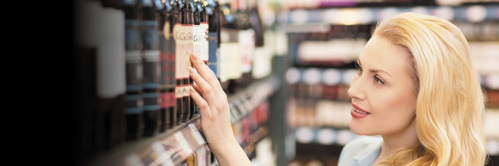 woman looks at glass wine bottles