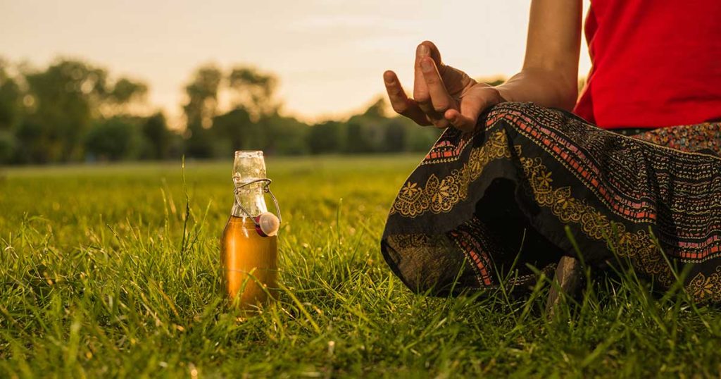 woman meditates with glass bottle